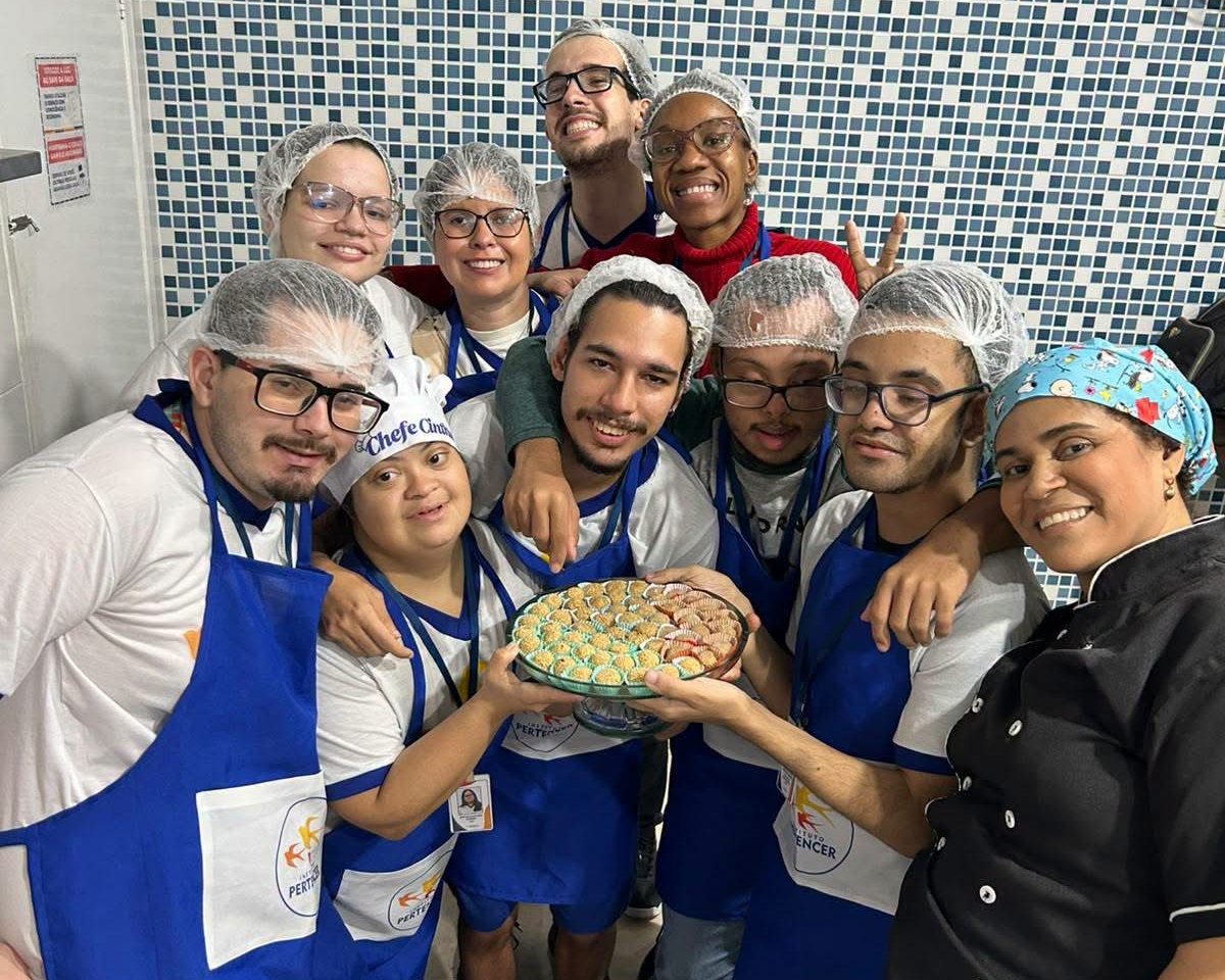 Turma de Auxiliar de Cozinha do AJA sorrindo com uma bandeja de docinhos feitos em aula